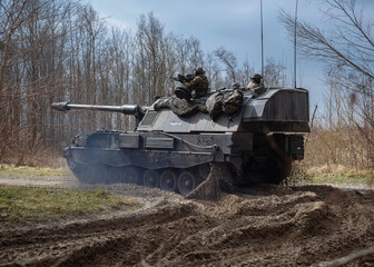PzH 2000NL artillery piece maneuvering through muddy terrain during training exercise with bare...