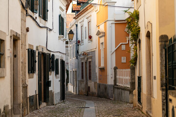 Visitors stroll along a picturesque street in Cascais, Portugal, where whitewashed buildings...