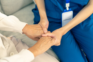Asian woman caregiver holding senior woman hands and consoling with empathy. Doctor or nurse visit and take care elderly patient at nursing home. Home medical healthcare service and health insurance.