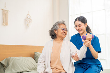 Asian woman physiotherapist caregiver teaching senior female patient exercise weight lifting...