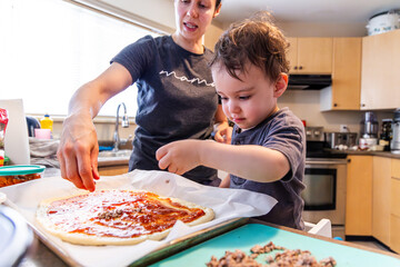 Mother and Toddler Son Cooking Pizza Together in a Bright Kitchen