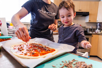 Mother and Toddler Boy Making Homemade Pizza Together in the Kitchen
