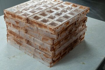 Dirty plastic molds for making chocolate squares_side view.