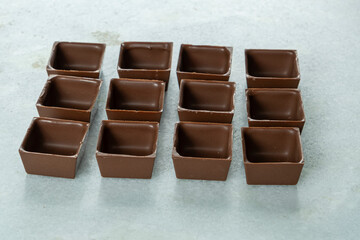 Square-shaped milk chocolate shells ready to be filled.