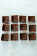 Square-shaped milk chocolate shells ready to be filled_side view_vertical.