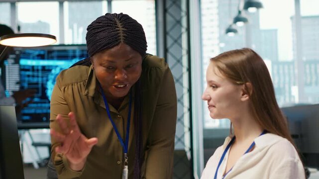 Pleased supervisor recognizing junior dev achievements at work, fostering positive office culture. Cheerful african american manager praising code written by female engineer, doing high five, camera A