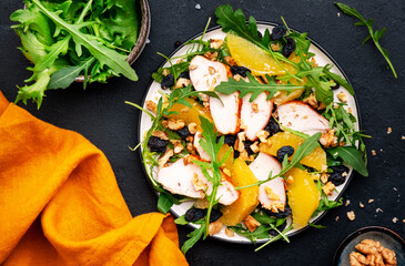 Winter salad with grilled chicken fillet, orange slices, raisins, walnut, arugula, spinach and...