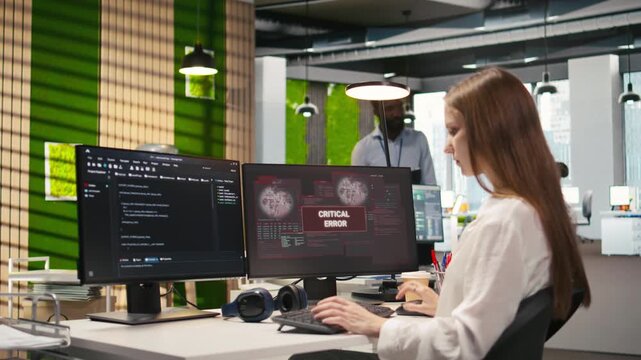Female engineer in startup office struggling to fix critical error warning popup. Intern doing maintenance on computer glitches while coding in software development agency, camera A