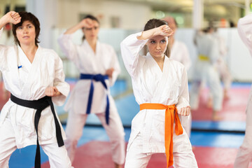 Young women in white kimono learn karate techniques. European women in self-defense training