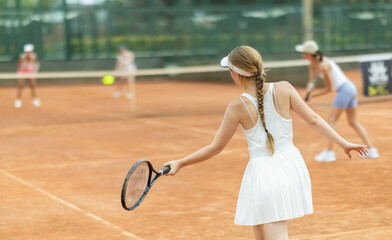 Young woman playing tennis against female opponent on tennis court