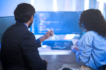 Diverse AI tech team reviewing code for a machine learning algorithm. Indian male and Hispanic...