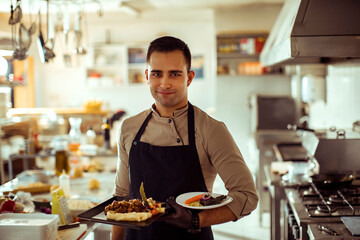 Portrait of a chef presenting plated meals in professional kitchen