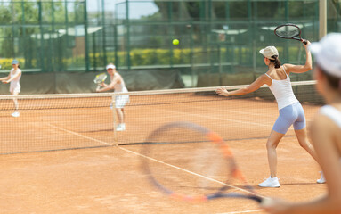 Young woman playing tennis against female opponent on tennis court