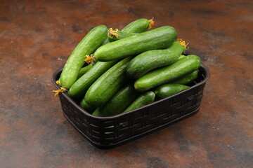 Fresh green cucumbers in a small wooden vegetable crate.