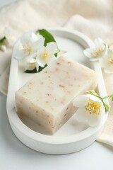 Soap bar and jasmine flowers on white table, closeup