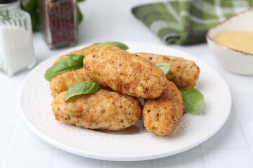 Tasty fried croquettes and basil on white tiled table, closeup