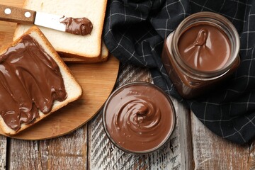Tasty chocolate butter and slices of bread on wooden table, flat lay