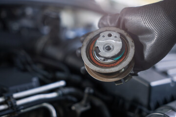 Auto part. Professional mechanic with idler-wheel near open hood of car indoors, closeup. Space for...
