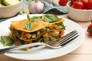 Piece of tasty vegetarian lasagna served on white wooden table, closeup