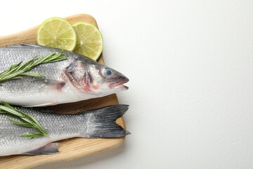 Fresh raw seabass fish with spices on white table, top view and space for text. Seafood delicacies