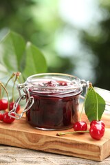 Tasty cherry jam and fresh fruits on wooden table against blurred background, closeup. Space for text