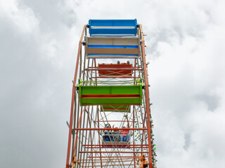 Composition of a portion of a Ferris wheel with a background of a sky with gray clouds.
