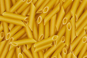 Full-length image of raw penne pasta, with a patterned background and copy space.
