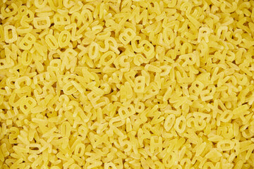 Full-length image of raw letter pasta, with a patterned background and copy space.