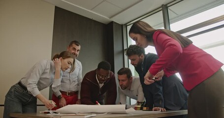 A multinational business team collaborates on a project, reviewing blueprints and celebrating their teamwork with a high five. - Powered by Adobe