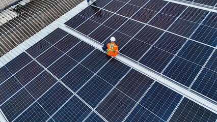 Solar power technician inspecting rooftop solar panels, performing maintenance and installation of...