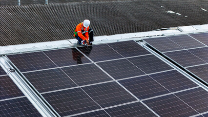 technician installs a large photovoltaic system on an industrial rooftop. ESG investment, and the...