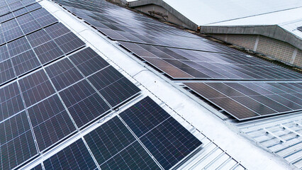 Aerial view of photovoltaic solar panels installed on the metal roof of a commercial building or...