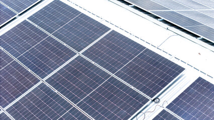 Aerial view of photovoltaic solar panels installed on the metal roof of a commercial building or...