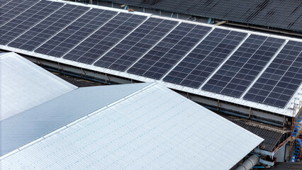 Aerial view of photovoltaic solar panels installed on the metal roof of a commercial building or...