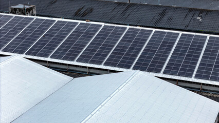 Aerial view of photovoltaic solar panels installed on the metal roof of a commercial building or...