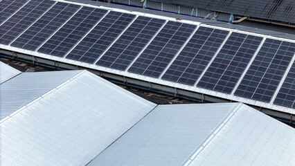 Aerial view of photovoltaic solar panels installed on the metal roof of a commercial building or...