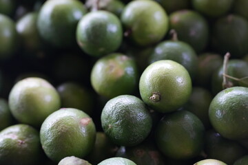many fresh green limes piled together. The limes have vibrant green color with slightly rough natural skin texture, showcasing freshness and quality of agricultural produce. Perfect for cooking