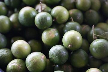 many fresh green limes piled together. The limes have vibrant green color with slightly rough natural skin texture, showcasing freshness and quality of agricultural produce. Perfect for cooking