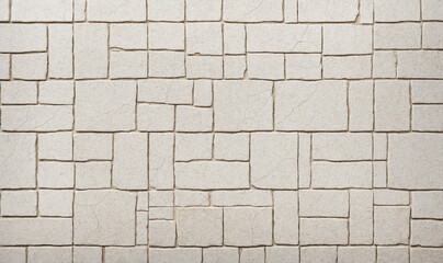 a rustic stone wall texture with beige tiles in an irregular pattern for a background