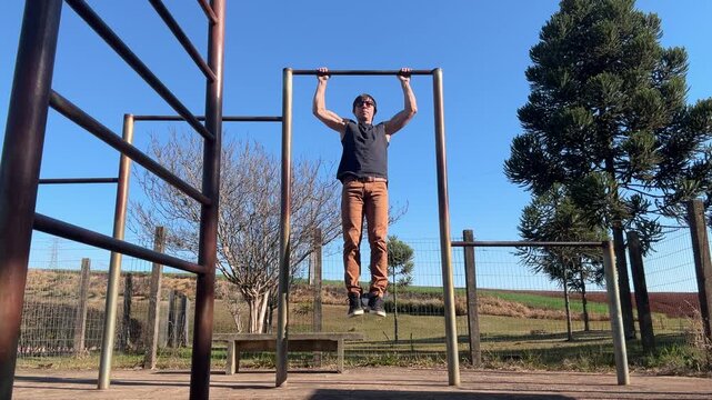 homem faz treino de calistenia exerc&iacute;cios em parque 
