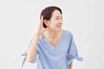 女性　ミドルエイジ　耳に手を当てて聞くジェスチャー　白背景