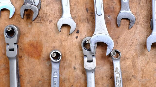 A collection of tools including wrenches and screwdrivers are displayed on a wooden surface. The tools are arranged in a way that they are all facing the viewer, creating a sense of organization