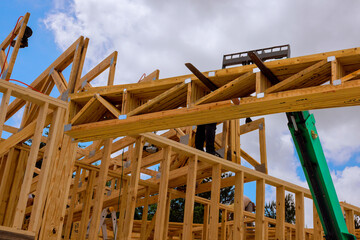 Skilled workers use cranes ladders to erect wooden beams for residential structure in progress...