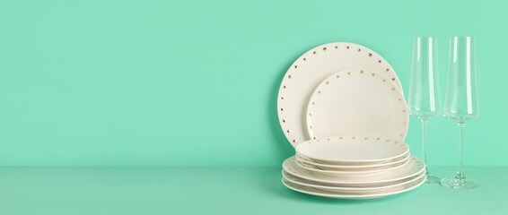 Clean glasses with plates on mint background with space for text
