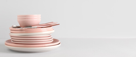 Clean plates with bowls and cutlery on light background with space for text