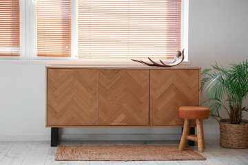 Chest of drawers with moose antler, stool and palm tree in room