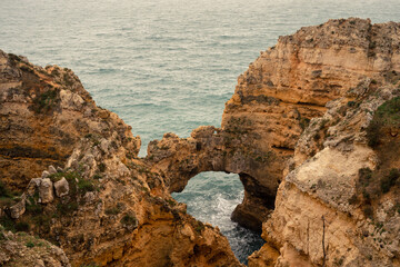 A breathtaking view of a natural limestone sea arch at Ponta da Piedade, showcasing the rugged, golden cliffs and turquoise Atlantic waters of the Algarve coast.