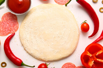 Raw dough and ingredients for preparing pizza on white background