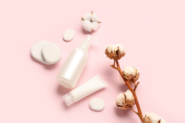 Cosmetic products, spa stones and cotton branch on pink background
