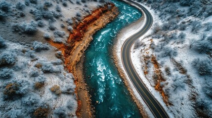 A winding icy river divides a snowy landscape, with a road tracing its path from above.